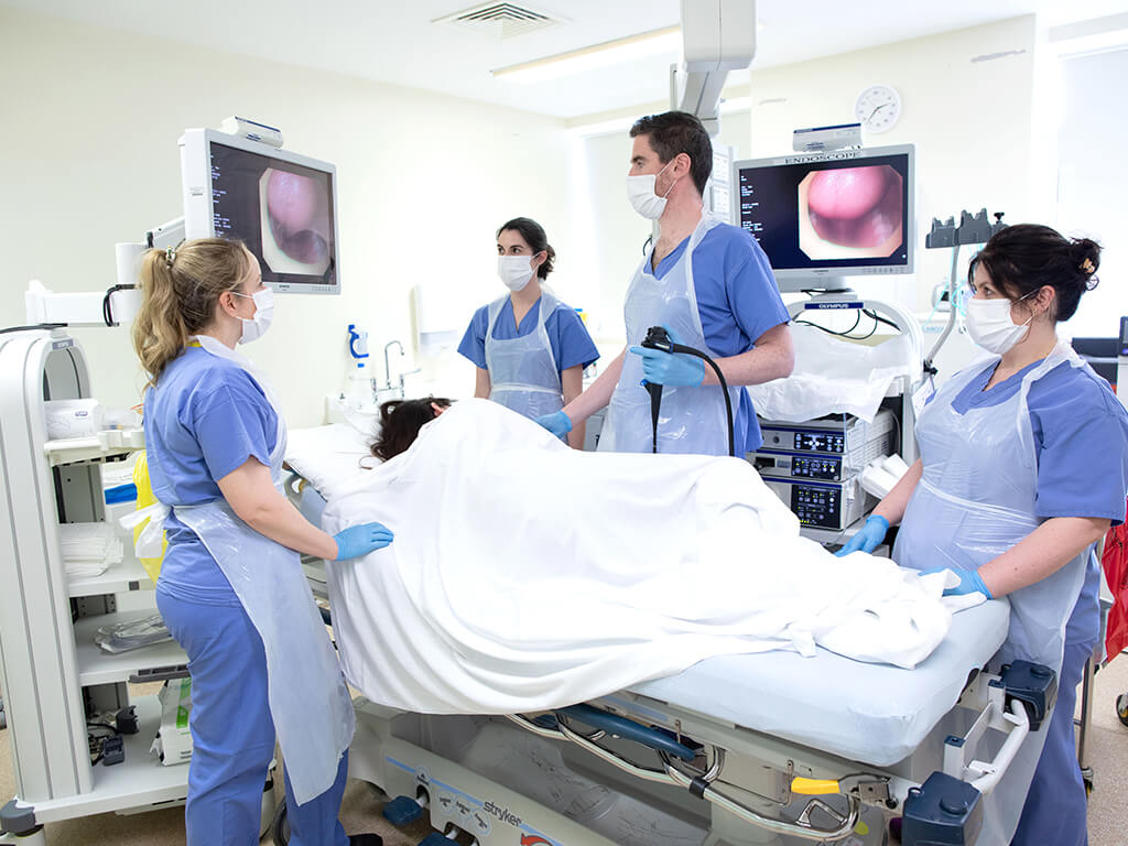 Doctors surround patient on bed during endoscopy